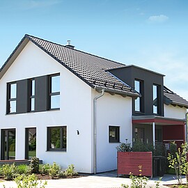 Haus mit Satteldach und schwarzer Gaube